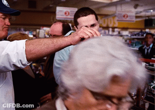 A Man In A Blue Hat Holds A Man 'S Hand Over His Face In A Store GIF