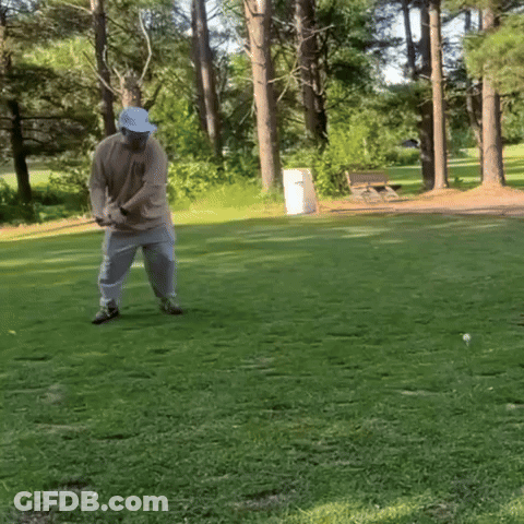 A Man In A Blue Hat Is Swinging A Golf Club On A Golf Course GIF