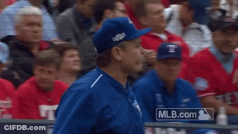 A Man In A Blue Hat Stands In Front Of A Mlb.com Logo GIF