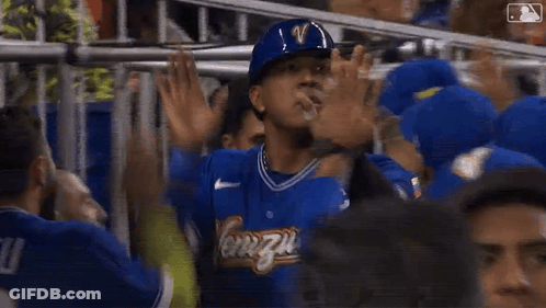 A Man In A Blue Helmet Is Standing In A Crowd Of People . GIF