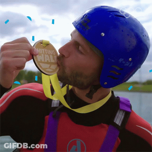 A Man In A Blue Helmet Kisses A Medal That Says Hitting Wall GIF