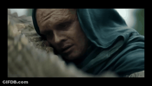 A Man In A Blue Hooded Cloak Is Laying On A Rock GIF
