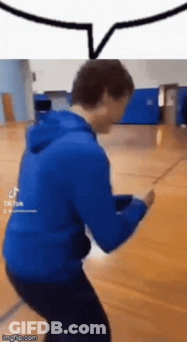 A Man In A Blue Hoodie Is Dancing On A Wooden Floor . GIF