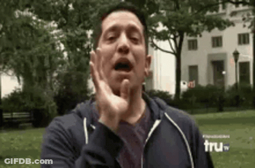 A Man In A Blue Hoodie Is Making A Funny Face In Front Of A Building . GIF