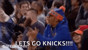 A Man In A Blue Hoodie Is Sitting In A Crowd Of People Watching A Basketball Game And Screaming . GIF