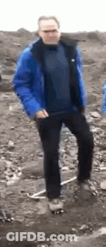 A Man In A Blue Jacket And Black Pants Is Dancing In The Dirt . GIF