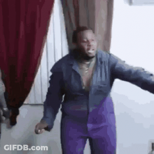 A Man In A Blue Jacket And Purple Pants Is Standing In A Room . GIF