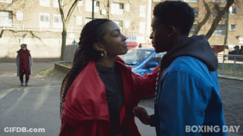 A Man In A Blue Jacket Holds The Hand Of A Woman In A Red Jacket With Boxing Day Written On The Bottom GIF