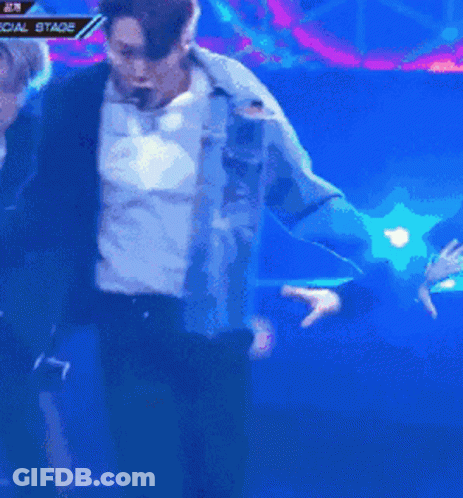 A Man In A Blue Jacket Is Dancing In Front Of A Special Stage Banner GIF