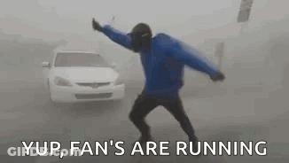 A Man In A Blue Jacket Is Dancing In Front Of A White Car In The Fog . GIF