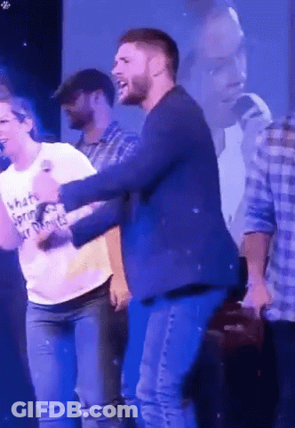 A Man In A Blue Jacket Is Dancing With A Woman In A White T-Shirt That Says What 'S Spring ? GIF