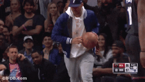 A Man In A Blue Jacket Is Holding A Basketball In Front Of A Crowd While Wearing A Number 1 Jersey GIF