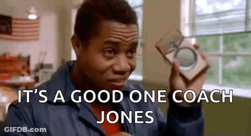 A Man In A Blue Jacket Is Holding A Piece Of Paper That Says It 'S A Good One Coach Jones GIF