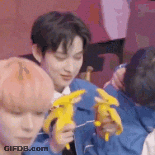 A Man In A Blue Jacket Is Holding A Stuffed Banana In His Hands . GIF