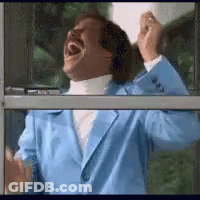 A Man In A Blue Jacket Is Laughing While Looking Out A Window . GIF