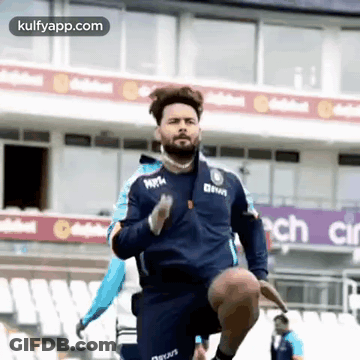 A Man In A Blue Jacket Is Running On A Stadium . GIF