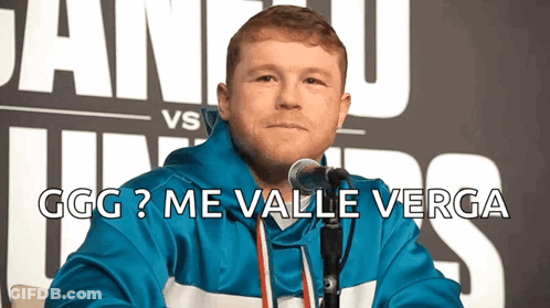 A Man In A Blue Jacket Is Sitting In Front Of A Microphone With The Words Ggg Me Valle Verga Below Him GIF