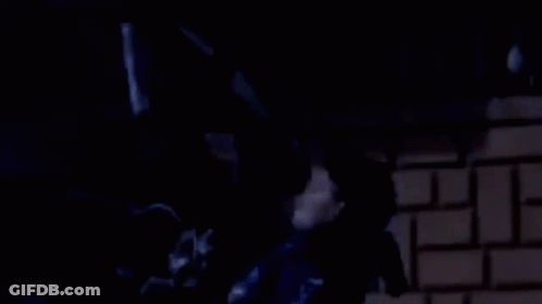 A Man In A Blue Jacket Is Standing In Front Of A Brick Wall With The Words Drai 3Ta9 GIF