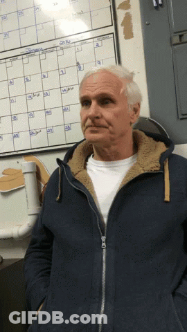 A Man In A Blue Jacket Is Standing In Front Of A Calendar That Shows The Month Of September GIF