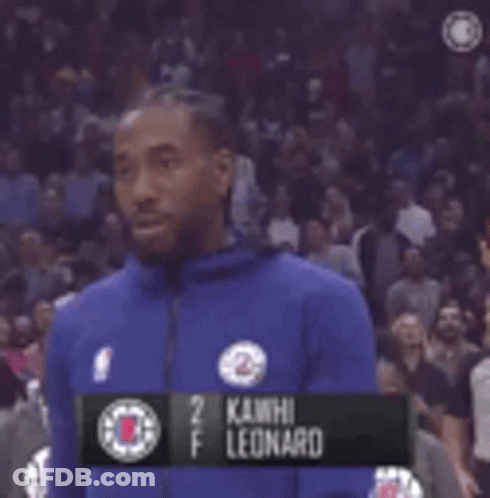 A Man In A Blue Jacket Is Standing In Front Of A Crowd In A Basketball Game . GIF