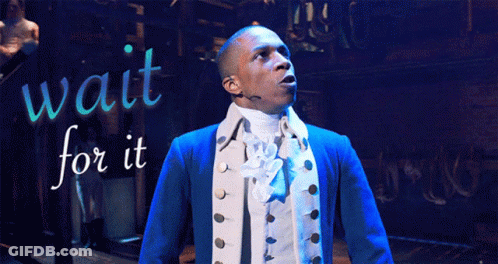 A Man In A Blue Jacket Is Standing In Front Of A Sign That Says Wait For It GIF