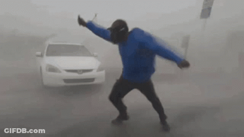 A Man In A Blue Jacket Is Standing In Front Of A White Car In The Fog . GIF