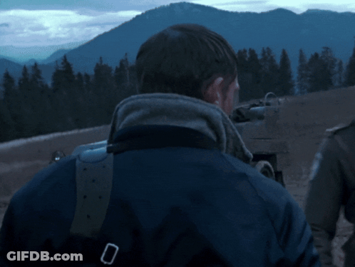 A Man In A Blue Jacket Is Standing In Front Of Mountains GIF