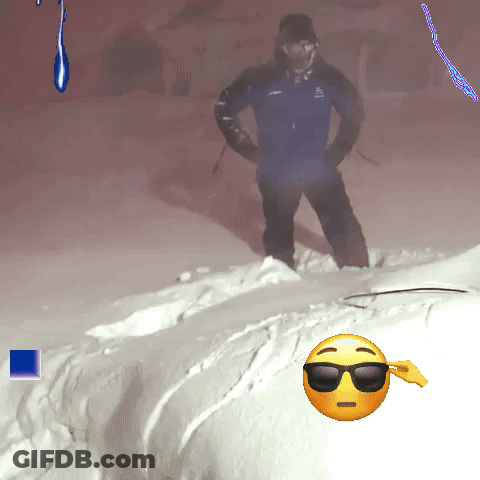 A Man In A Blue Jacket Is Standing In The Snow Next To A Smiley Face With Sunglasses On GIF
