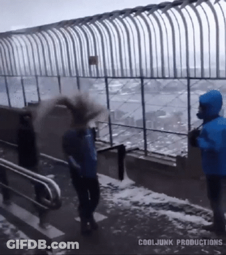 A Man In A Blue Jacket Is Throwing Snow At Another Man In A Blue Jacket GIF