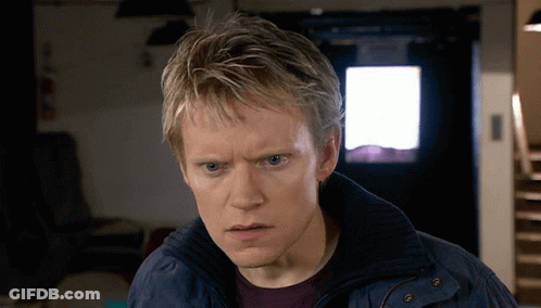 A Man In A Blue Jacket Looks At The Camera With A Serious Look On His Face GIF
