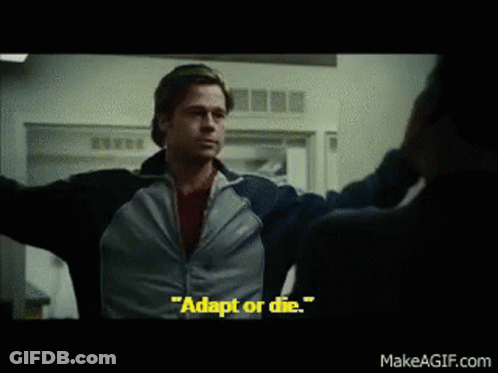 A Man In A Blue Jacket Says " Adapt Or Die " In A Movie Scene GIF