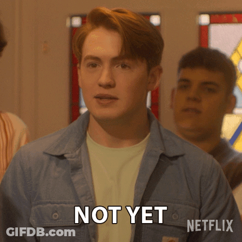 A Man In A Blue Jacket Says Not Yet In Front Of A Stained Glass Window GIF