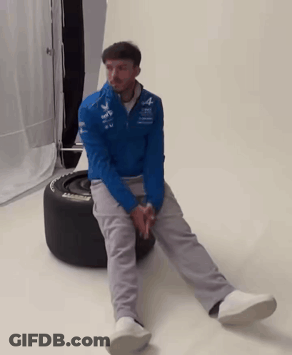 A Man In A Blue Jacket Sits On A Tire That Says Michelin On It GIF