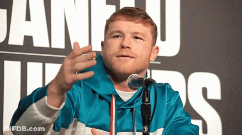 A Man In A Blue Jacket Speaking Into A Microphone In Front Of A Sign That Says Juan Luis GIF