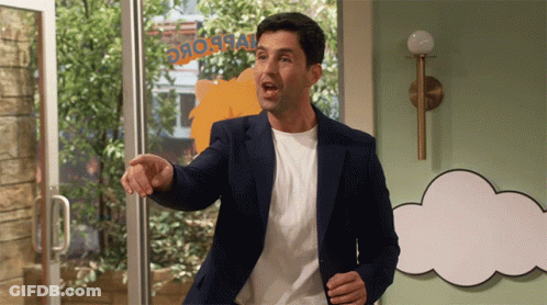 A Man In A Blue Jacket Stands In Front Of A Sign That Says ' Dinosaur ' On It GIF