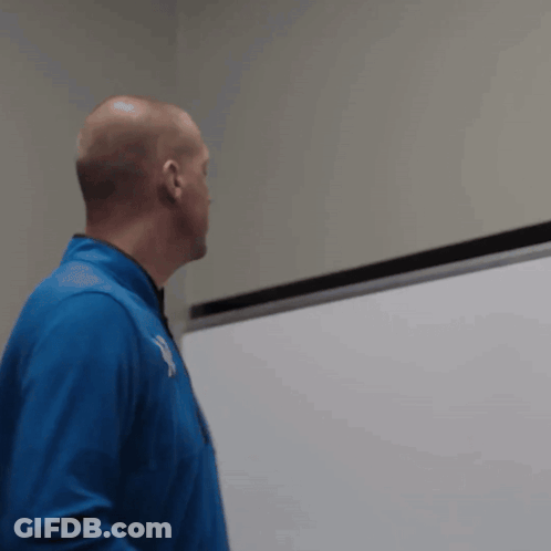 A Man In A Blue Jacket Stands In Front Of A White Board With The Letter Y On It GIF