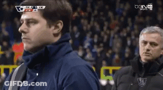 A Man In A Blue Jacket Stands Next To A Man In A Black Jacket With The Word Chelsea On It GIF