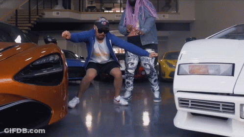 A Man In A Blue Jacket Stands Next To A Woman In Pink Hair GIF