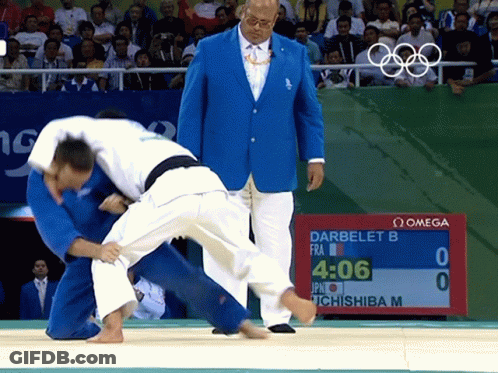 A Man In A Blue Jacket Watches A Judo Match Between Darbelet B And Ichishiba M GIF