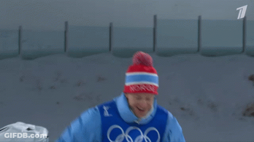 A Man In A Blue Jacket With The Word Biathlon On His Chest GIF