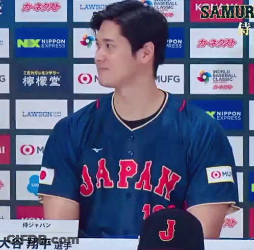 A Man In A Blue Japan Jersey Stands In Front Of A Wall Of Logos GIF
