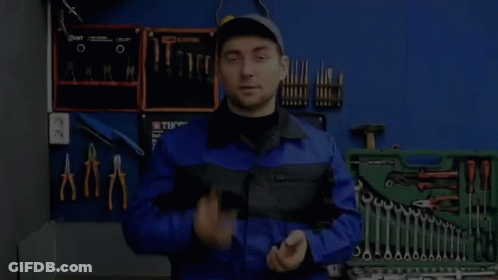 A Man In A Blue Jumpsuit Is Standing In Front Of A Toolbox Filled With Tools . GIF