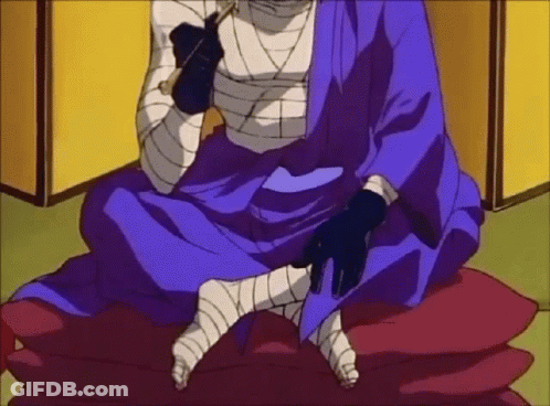 A Man In A Blue Kimono Is Sitting On A Red Pillow With Bandaged Legs . GIF