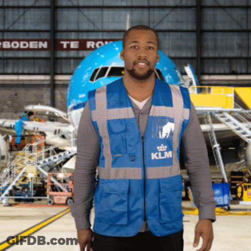 A Man In A Blue Klm Vest Stands In Front Of A Plane GIF