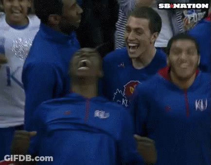 A Man In A Blue Ku Shirt Is Screaming In A Crowd Of People GIF