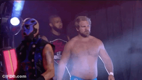 A Man In A Blue Mask Is Standing Next To A Man In A Red Shirt With The Word Life On It . GIF