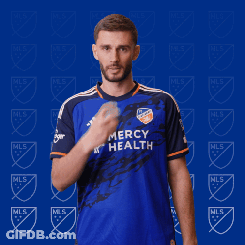 A Man In A Blue Mercy Health Jersey Holds His Finger To His Lips GIF