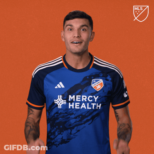 A Man In A Blue Mercy Health Jersey Holds His Fist Up GIF