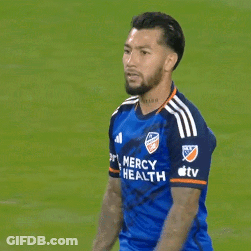 A Man In A Blue Mercy Health Jersey Stands On A Field GIF