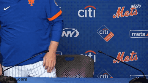 A Man In A Blue Mets Jersey Sits At A Table With Microphones In Front Of A Wall That Says Citi Field GIF